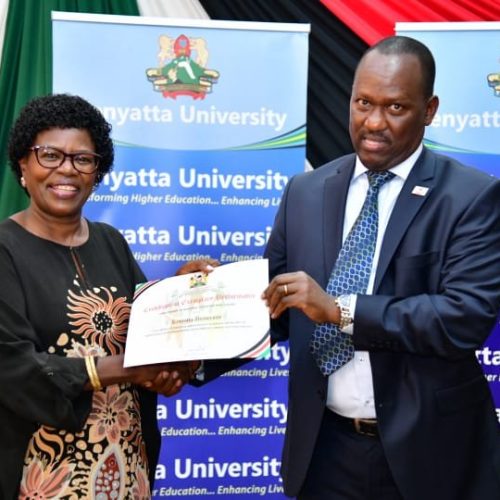 Secretary National Cohesion and Values, Mr Josiah Musili, EBS issuing a certificate to Ag. Vice Chancellor, Kenyatta University Prof. Waceke Wanjohi for exemplary performance in mainstreaming promotion of national values and principles of governance in University programmes.